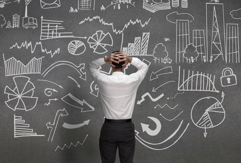 man standing in front of blackboard filled with notes, feeling overwhelmed