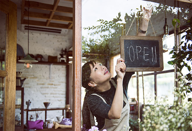 Woman hanging 'open' sign in shop window