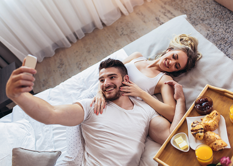 couple taking photo on bed in hotel