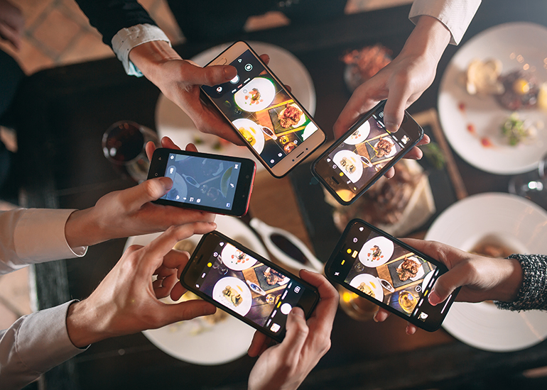 diners using phones to take photos of meal in restaurant / cafe