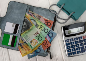 Open wallet with cash and calculator on desk