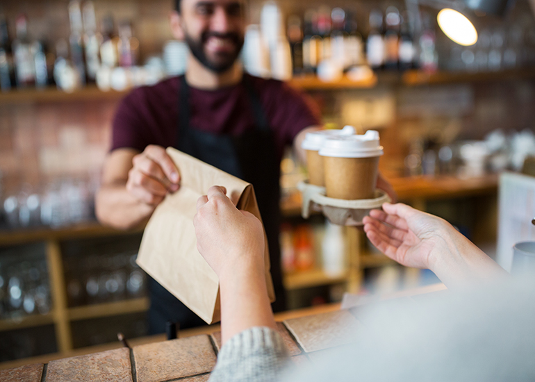 Cafe worker handing coffee order to customer