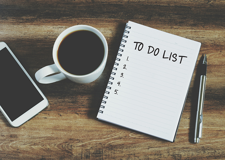 To do list on notepad next to coffee and phone