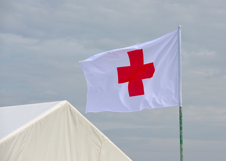 Red Cross flag flying next to tent