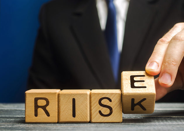 Businessman changes wooden blocks with the words Risk and Rise.