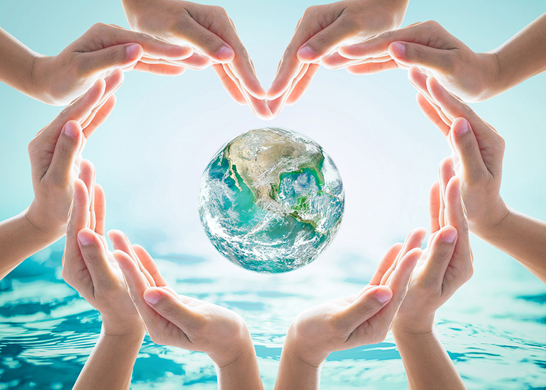 hands linked around a globe with ocean background