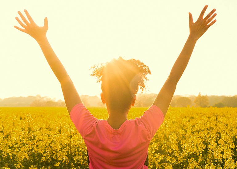 Happy woman with arms raised in a field of flowers