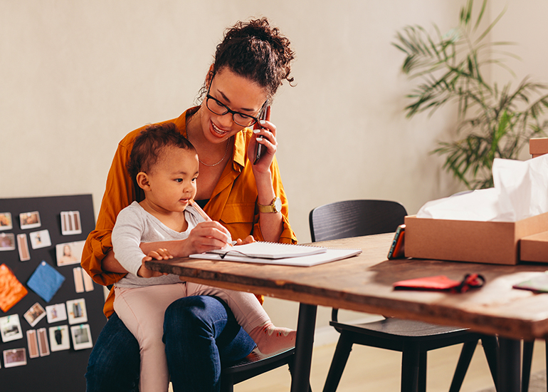 Toddler sitting in motherโ lap while she works at home