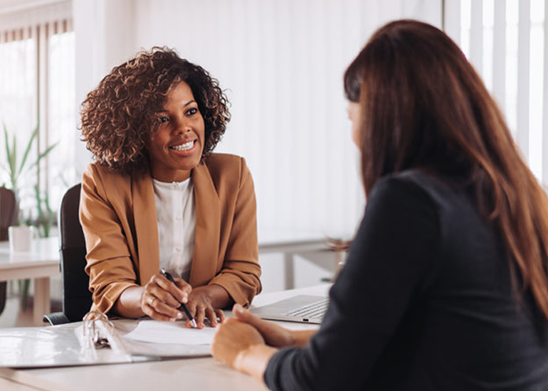 Two women sitting at desk looking at business documents