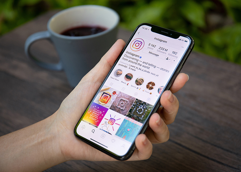 Hand holding smartphone with Instagram on screen