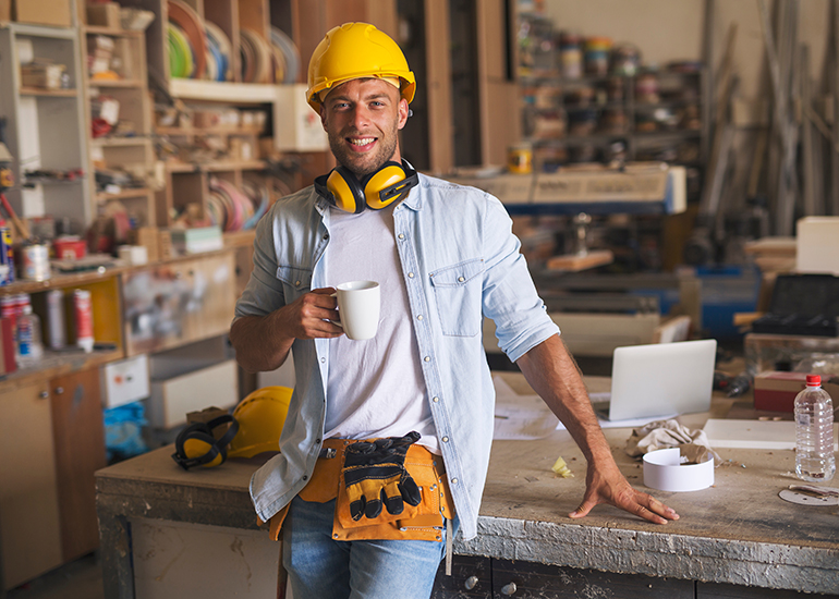 Carpenter relaxing with coffee in workshop