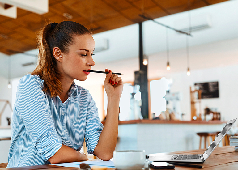 woman writing on laptop looking thoughtful