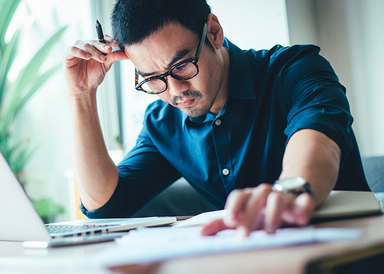 Young man looking worried over recieipts and financial papers