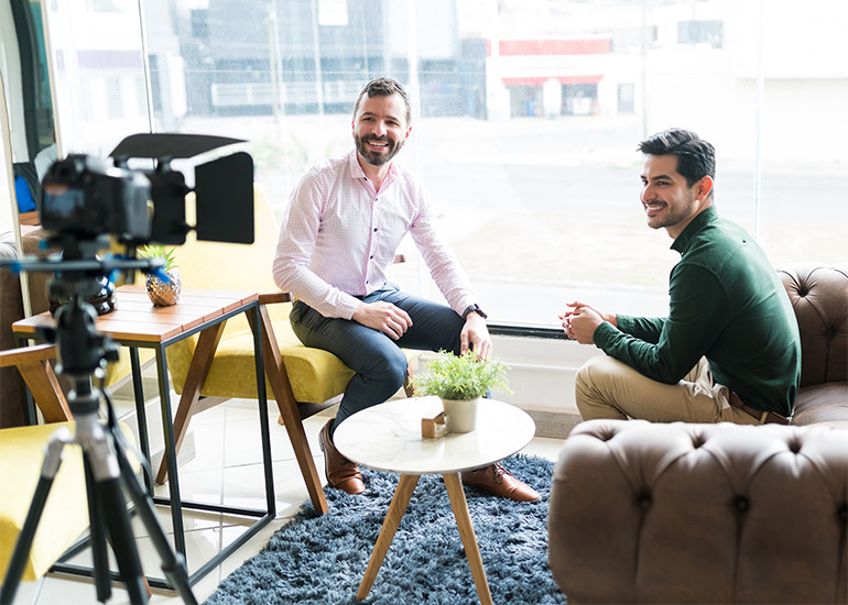 Two men sitting in front of camera for media interview