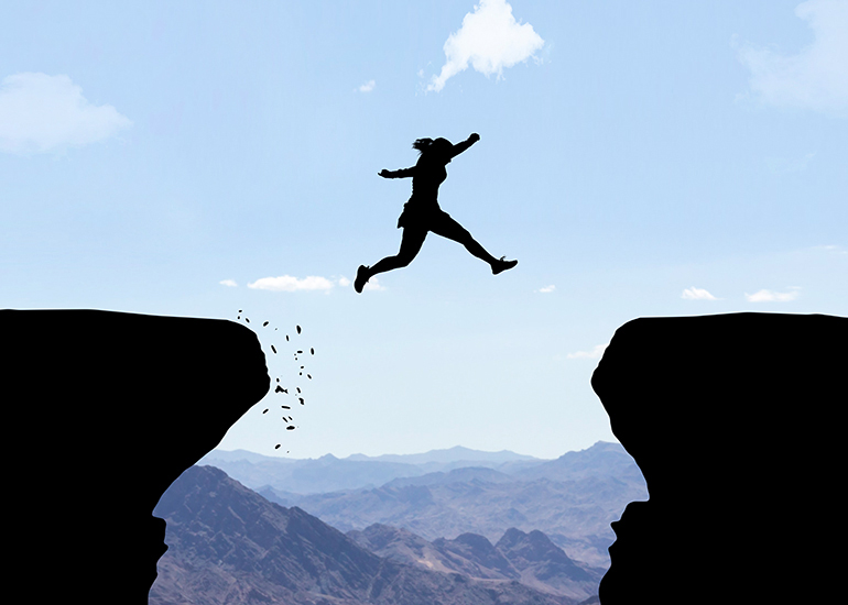 woman jumping between two cliffs on mountain top