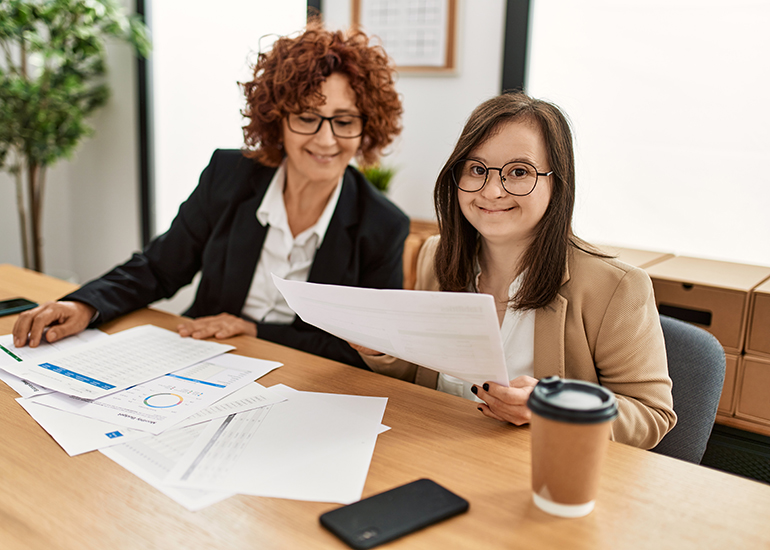 Mature woman and down syndrome girl working at inclusive company