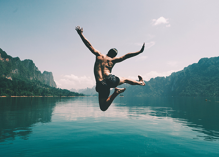 Man jumping joyfully into a lake