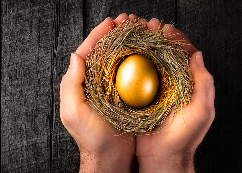 Hands holding a golden egg in a nest