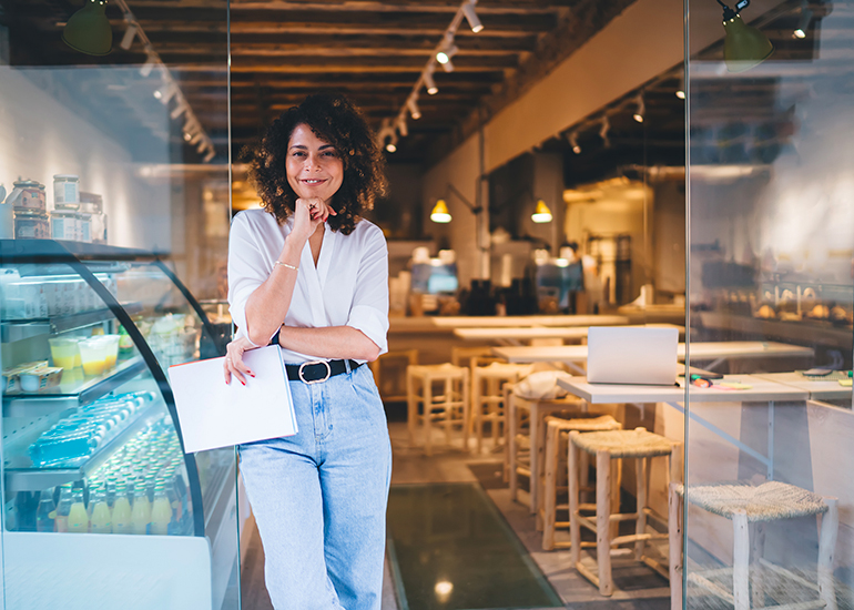 Female business owner standing at door of her restaurant