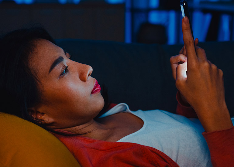 woman scrolling phone in bed at night