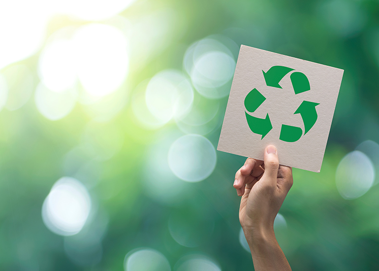 Hand holding card with green recycling symbol