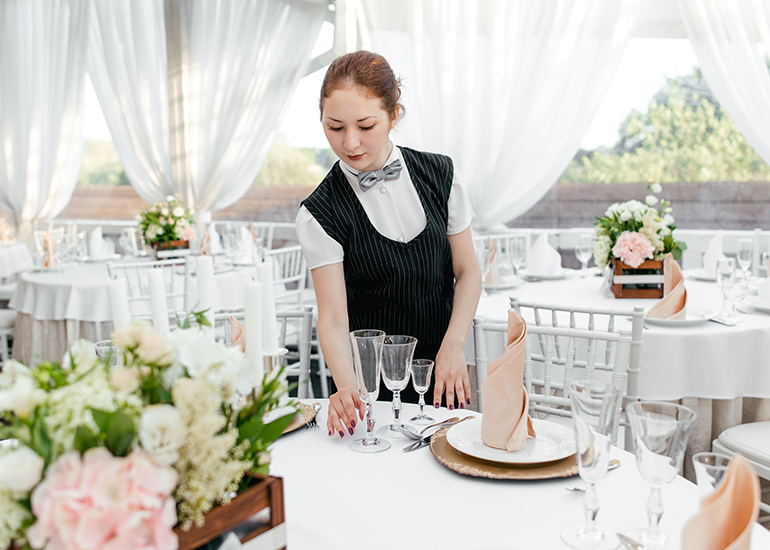 Young woman setting tables for event in marquee