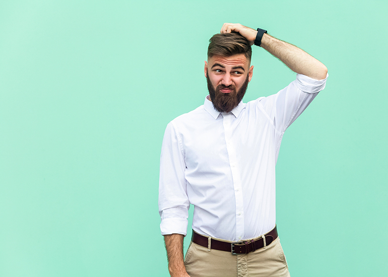 Young business man scratching head and looking confused