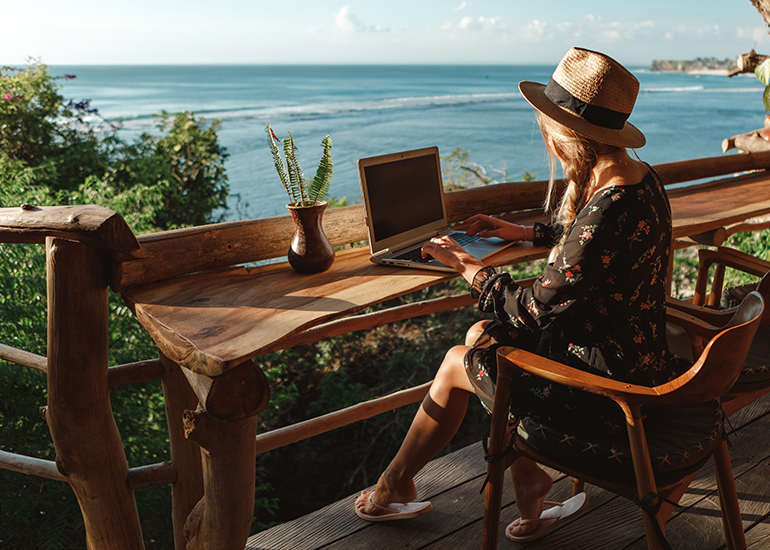 Woman working on resort verandah overlooking the ocean