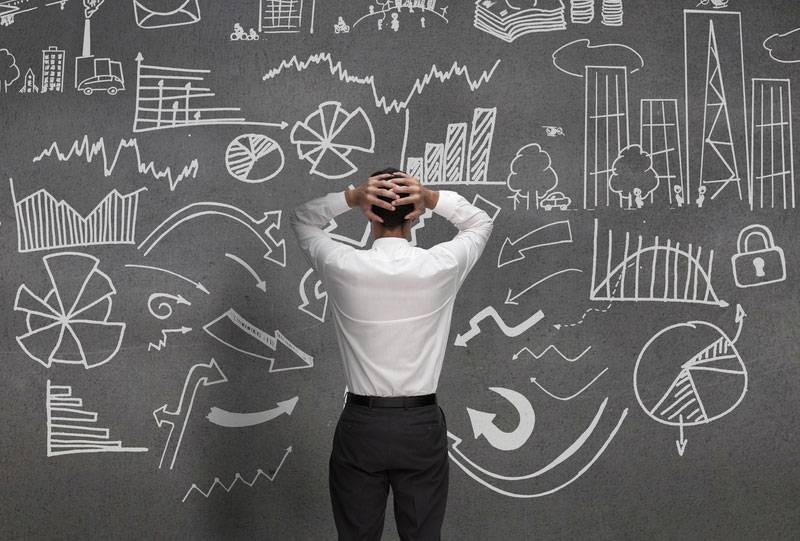 man standing in front of blackboard filled with notes, feeling overwhelmed