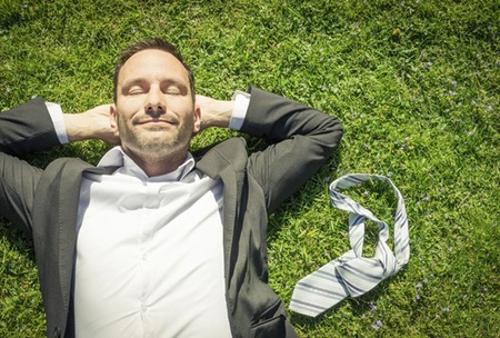 Man in business suit resting on grass with his tie off