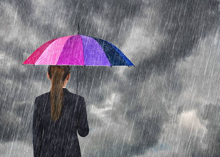 woman standing in the rain under rainbow umbrella