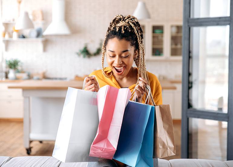 Delighted woman looking into shopping bags with surprise