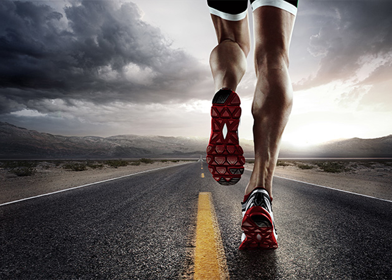 Back of runner's legs as they jog along an empty road