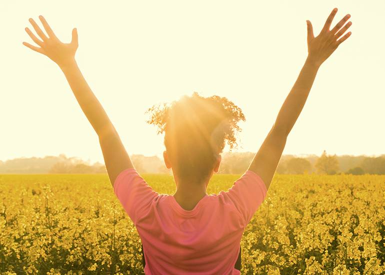 Happy woman with arms raised in a field of flowers