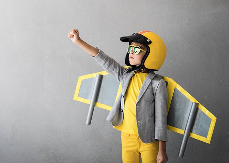 Confident kid in pilot and rocket costume symbolising small business firing on all cylinders