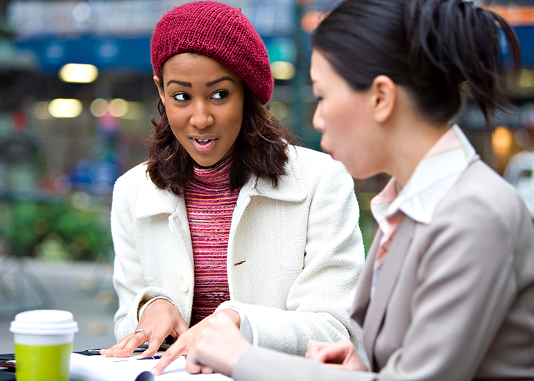 Two women sitting outdoors discussing business