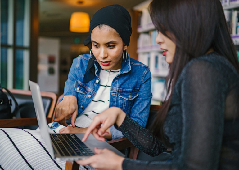 Two women in design meeting, pointing out issues on laptop