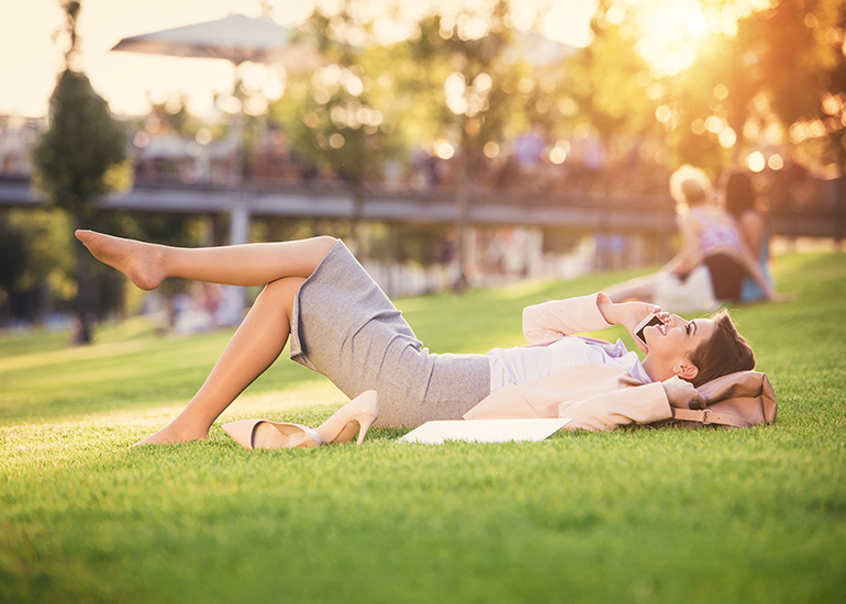 Woman in business suit relaxing on grass with shoes off