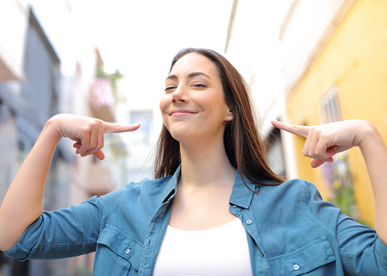 Smiling woman pointing to herself, feeling proud