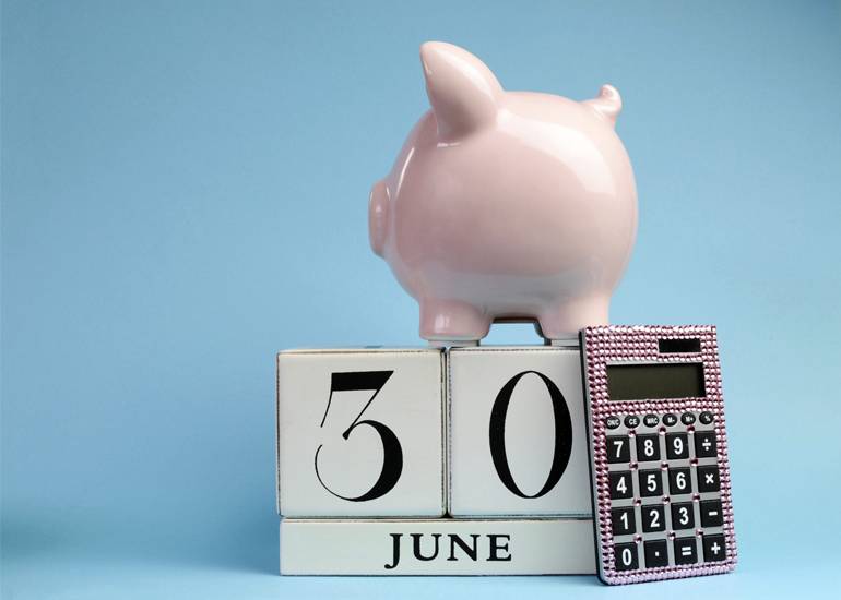 pink piggy bank and calculator with calendar showing 30 June