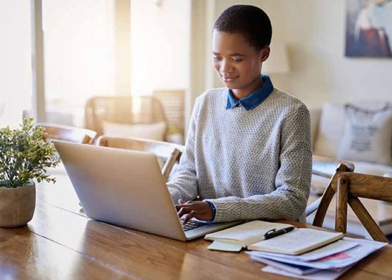 Woman working at table at home with laptop