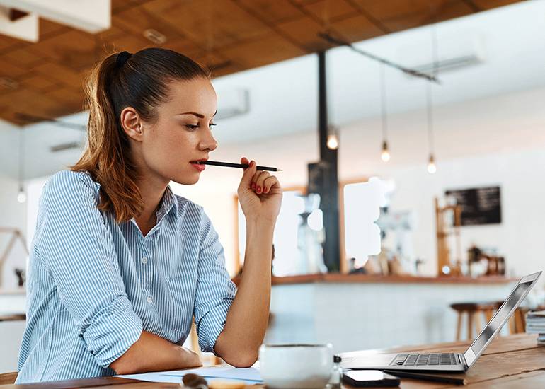 woman writing on laptop looking thoughtful