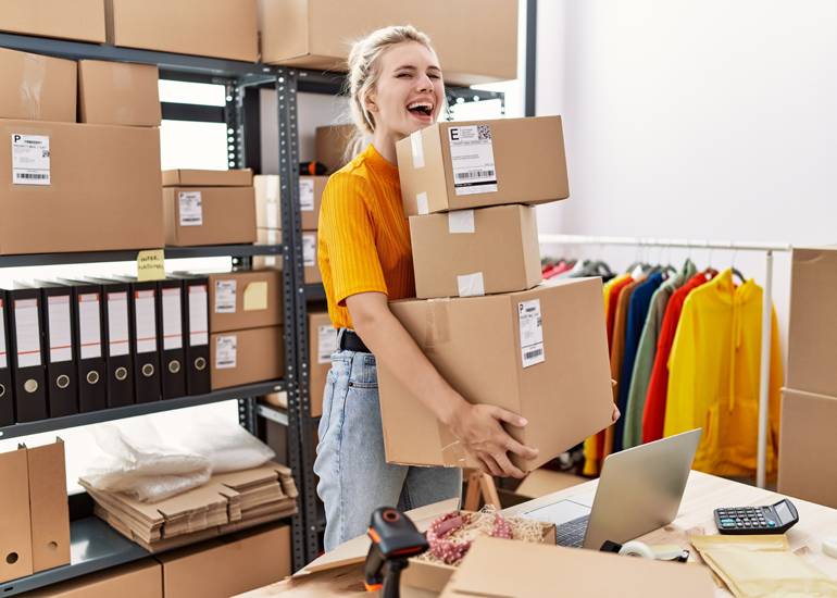 happy woman carrying boxes in warehouse office online business