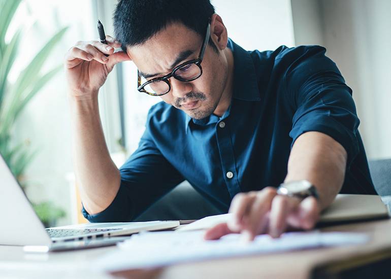 Young man looking worried over recieipts and financial papers