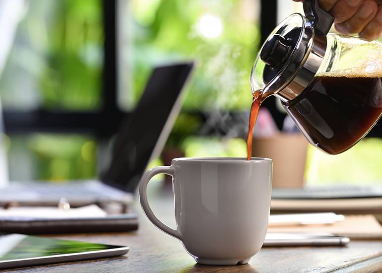 Pouring coffee into cup on desk