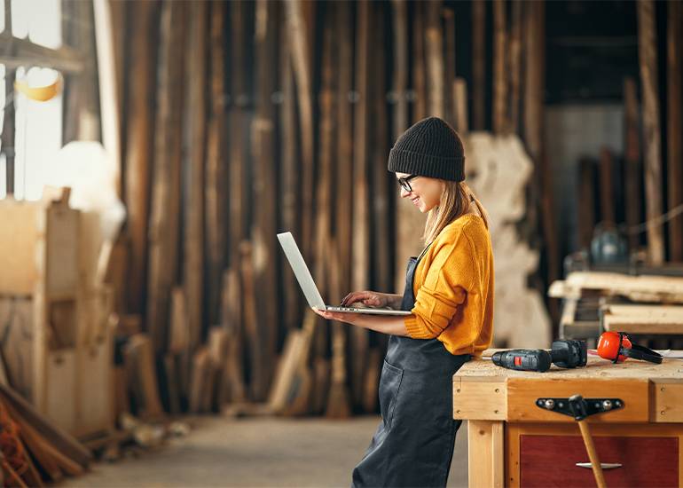 Female tradesperson using laptop in workshop