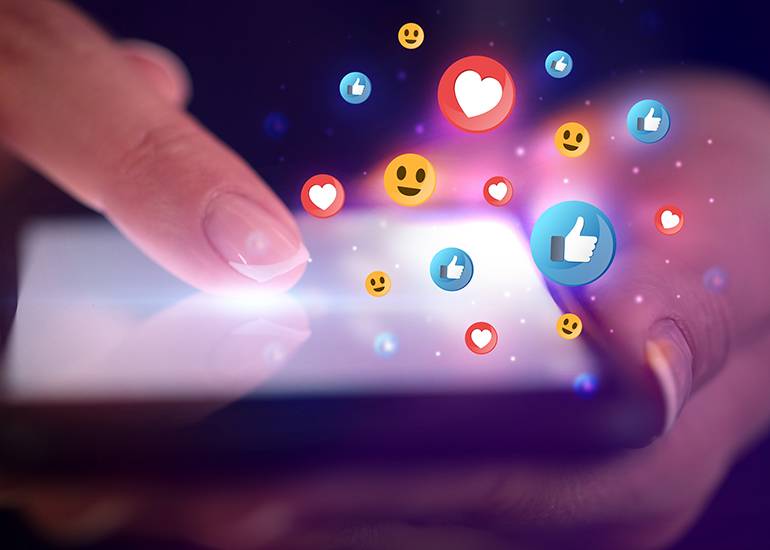 Woman's hand using smartphone with social media reactions surrounding