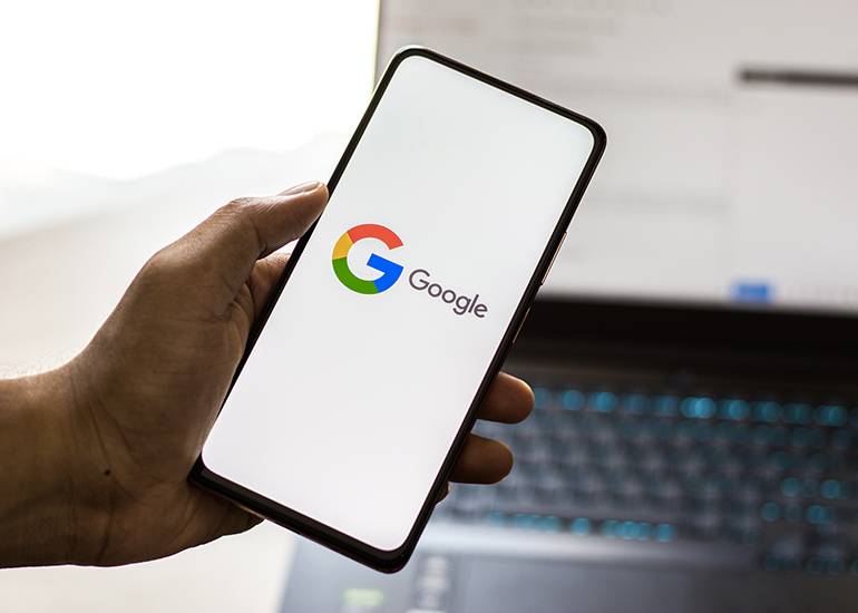 Hand holding phone with Google opening page on screen