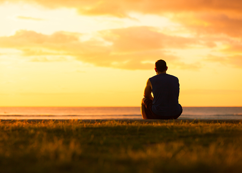 man sitting alone at ocean shore