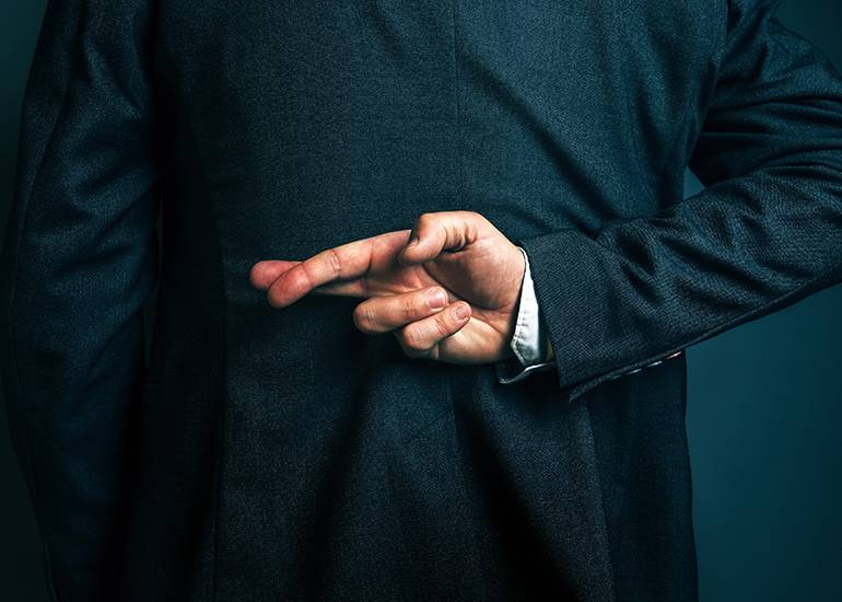 Man in business suit with fingers crossed behind back